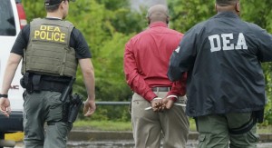 An unidentified man, center, is escorted from a medical clinic in Little Rock, Ark., by Drug Enforcement Administration officers on May 20, 2015. Early-morning raids in Arkansas, Alabama, Louisiana and Mississippi were the final stage of an operation launched last summer by the DEA's drug diversion unit, a senior DEA official said. (Danny Johnston, AP)