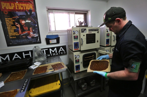 Professional extractor Jeremy Johnson removes a sheet of THC concentrate known as shatter from the oven at Mahatma Concentrates in Denver on May 1, 2014. (Brennan Linsley/Associated Press)