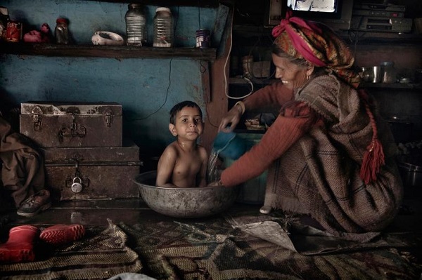A local woman bathes her grandson in the tandoori (wood stove) room of their house. PHOTOGRAPH BY ANDREA DE FRANCISCIS