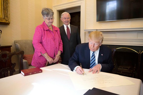 PRESIDENT TRUMP SIGNING PAPERWORK IN FRONT OF JEFF SESSIONS AND SESSIONS' WIFE. IMAGE SOURCE: DONALD J. TRUMP OFFICIAL FACEBOOK PAGE. PHOTO BY BENJAMIN D. APPLEBAUM.